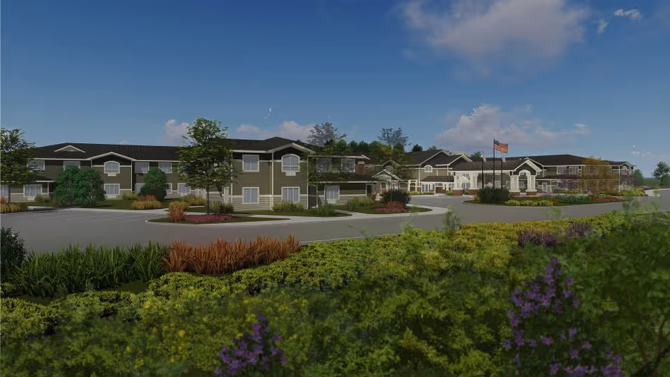 Wide view of a senior living campus with connected buildings, parking, and landscaped grounds.