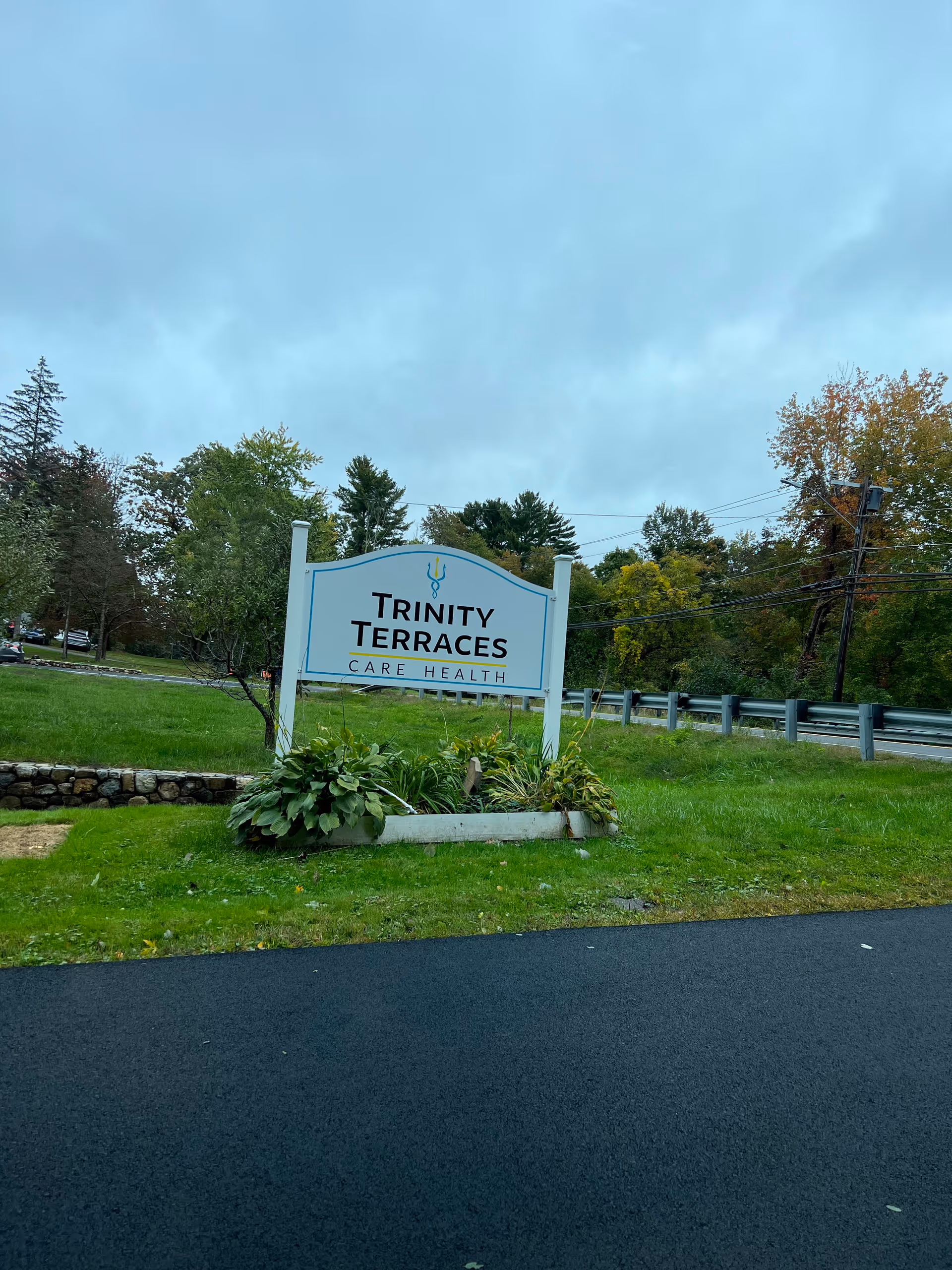 Exterior view of a grassy roadside with a Trinity Terraces sign and landscaping.