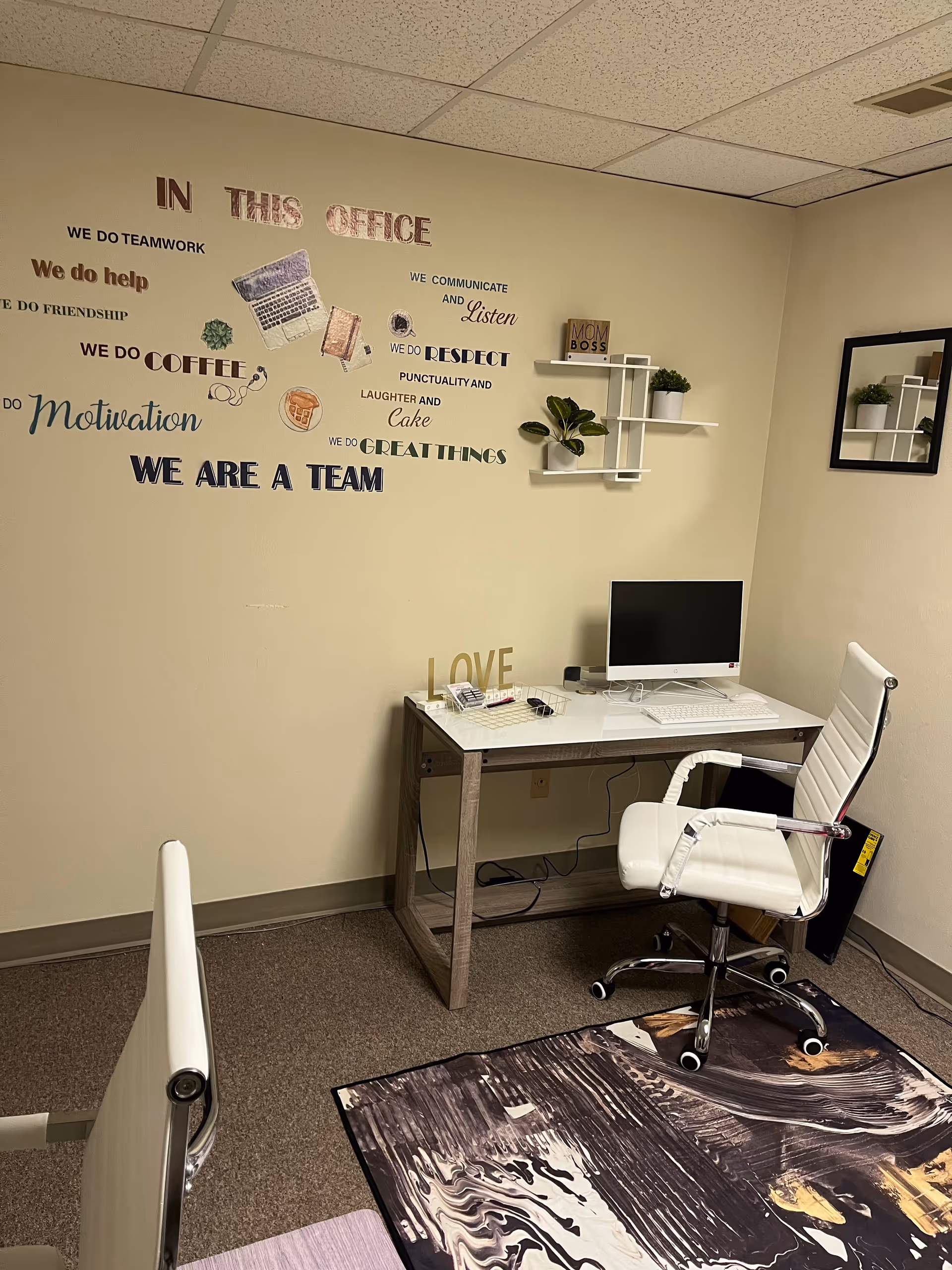 Office workspace in a care facility featuring a desk, computer, white chair, and wall decals.