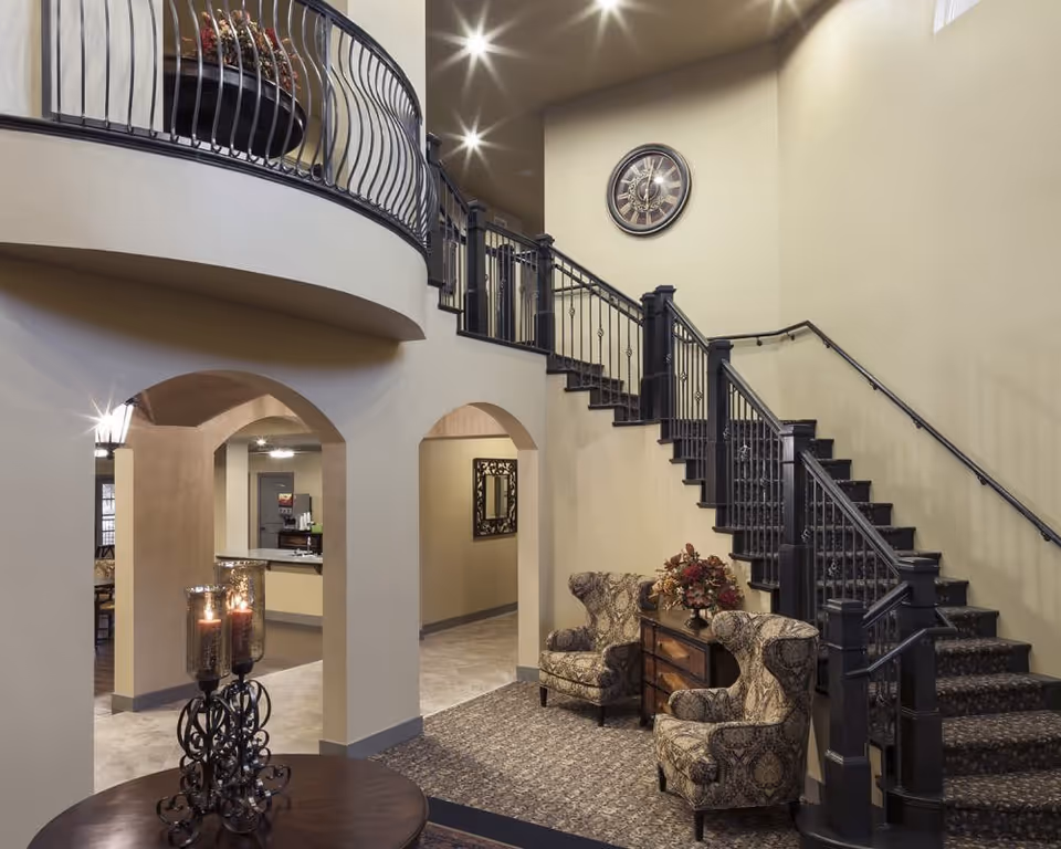 Two-story interior lobby with curved balcony, grand staircase, arches, and seating area