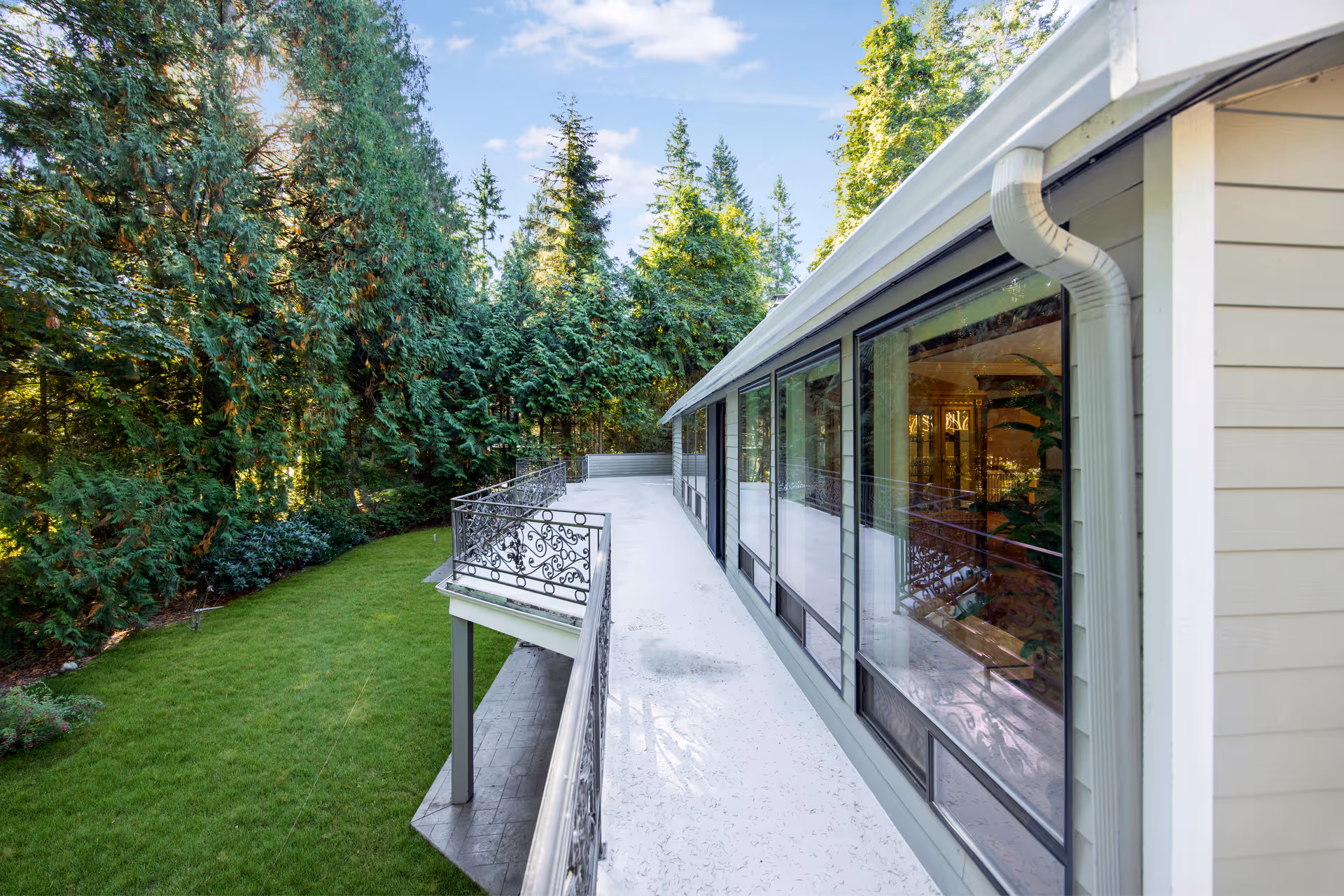 Exterior walkway along a modern building with large windows and surrounding trees.