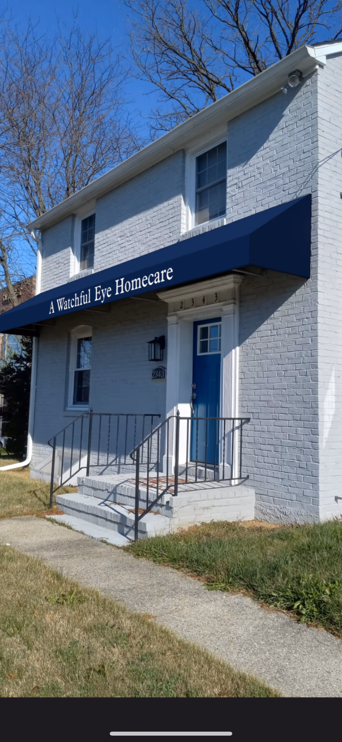 White brick building with blue awning over front entrance labeled A Watchful Eye Homecare.
