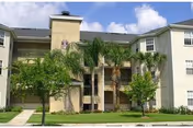 Front view of Windsor Park Apartments building with palm trees and manicured landscaping.