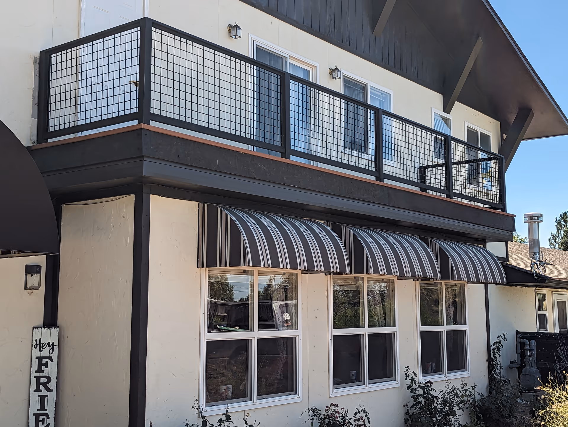 Two-story building with striped awnings over large windows and a balcony on the upper level.