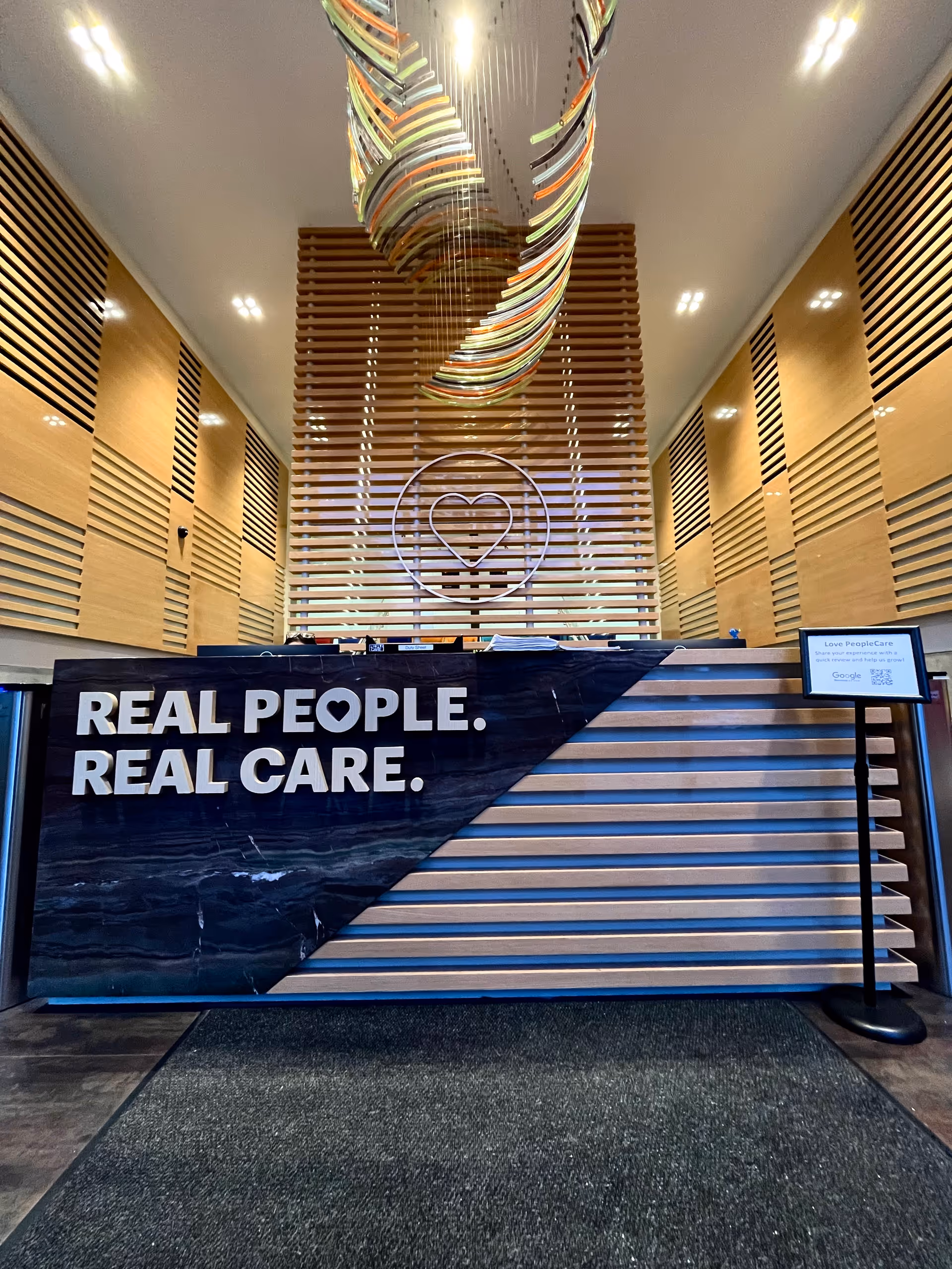 Reception area inside a senior living lobby with wood panels and a heart logo.