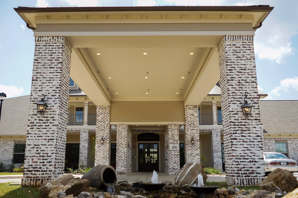 Exterior brick-and-stone entrance with tall columns and a covered portico at the main door.
