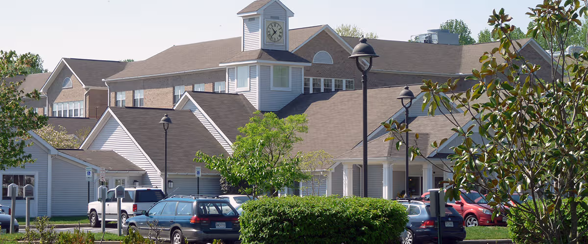 Exterior view of Collington, a Kendal Affiliate, with a clock tower and parked cars.