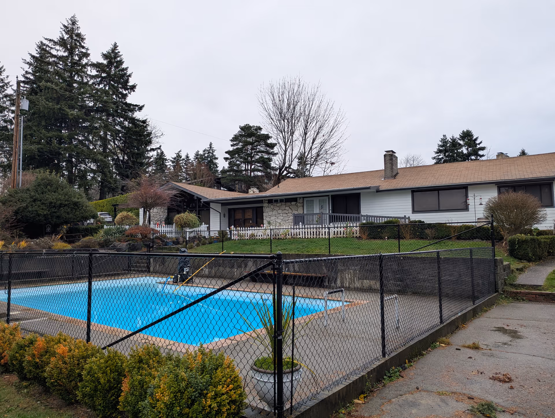 Single-story senior living home with a fenced outdoor pool and landscaped surroundings