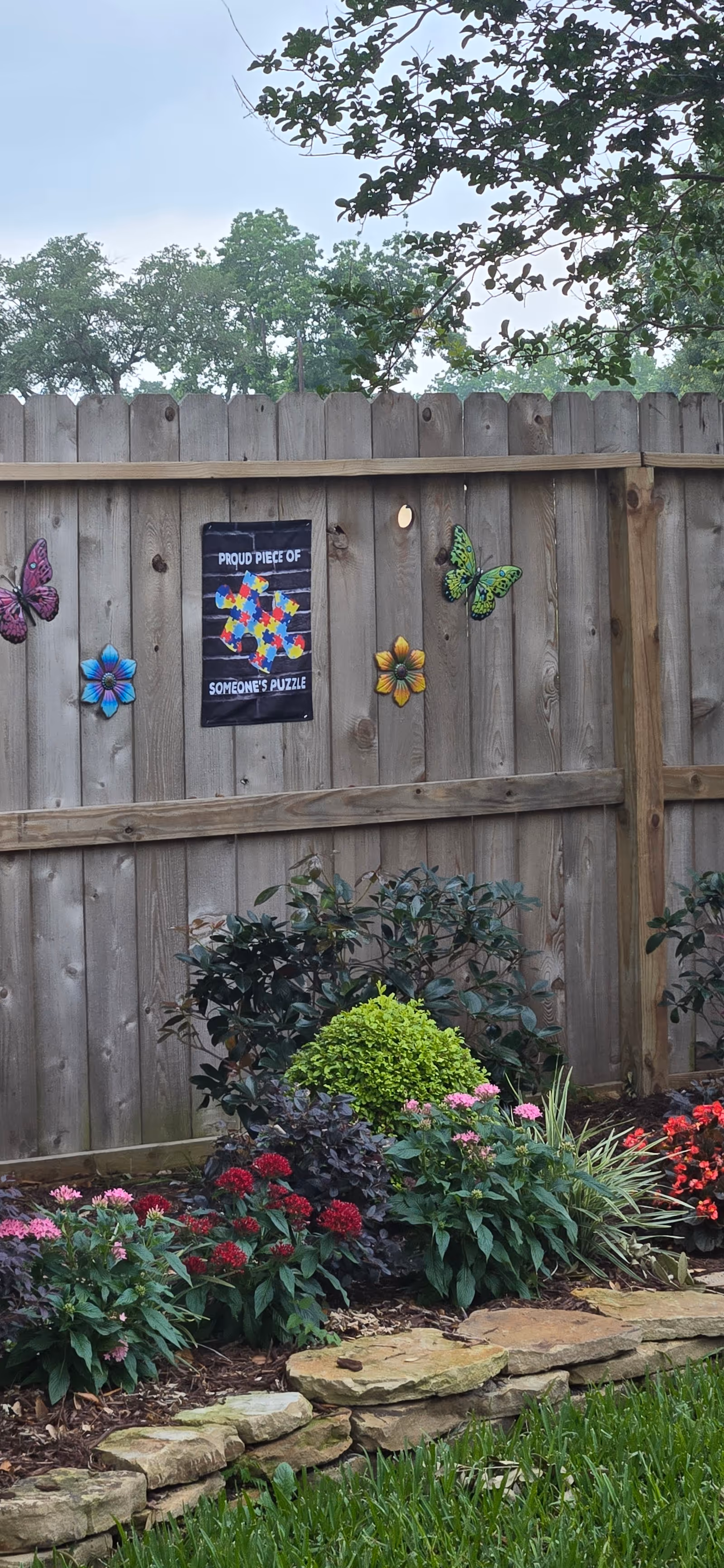 Wooden backyard fence with butterfly decorations and a flower garden.