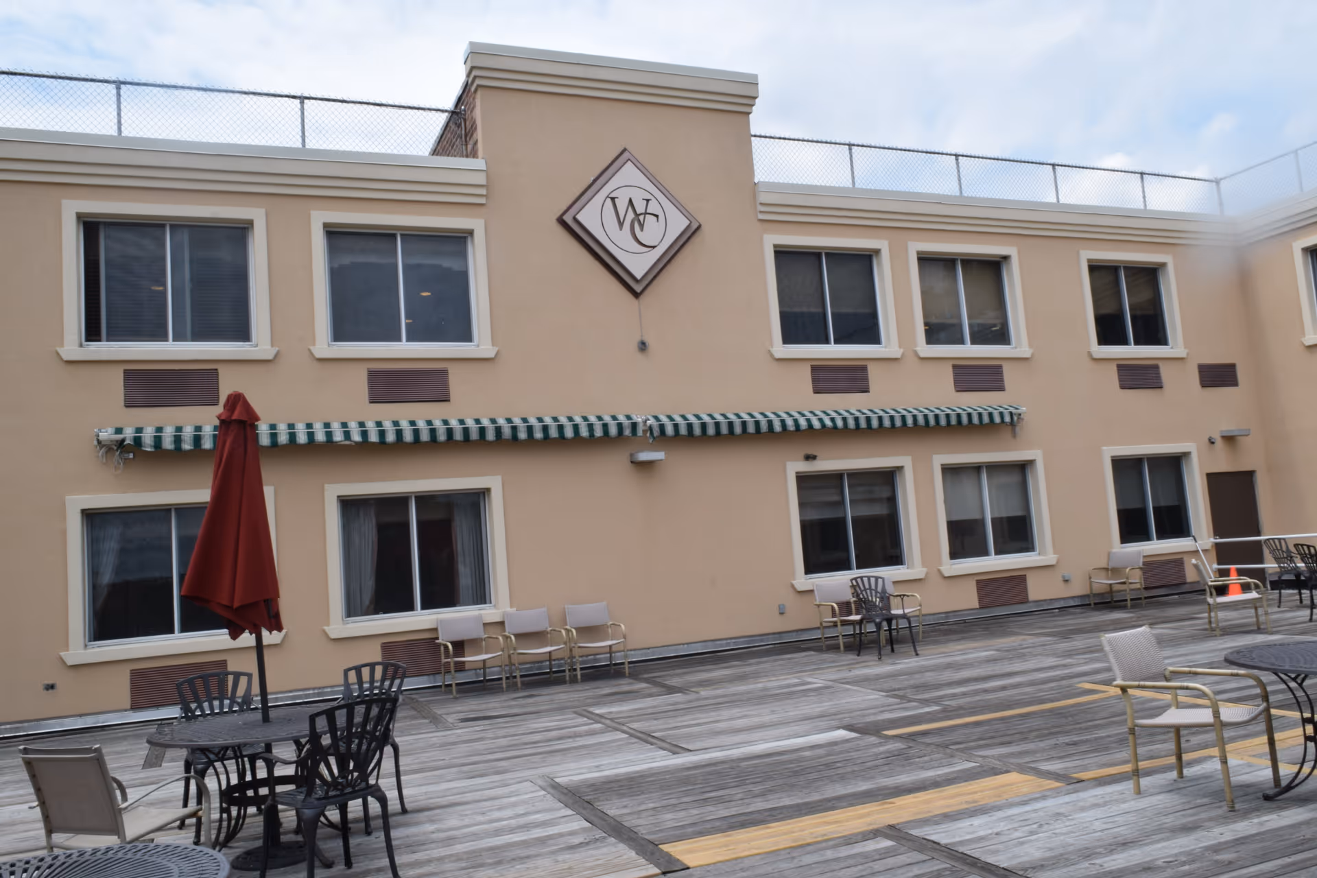 Exterior view of a beige senior facility with outdoor patio furniture.