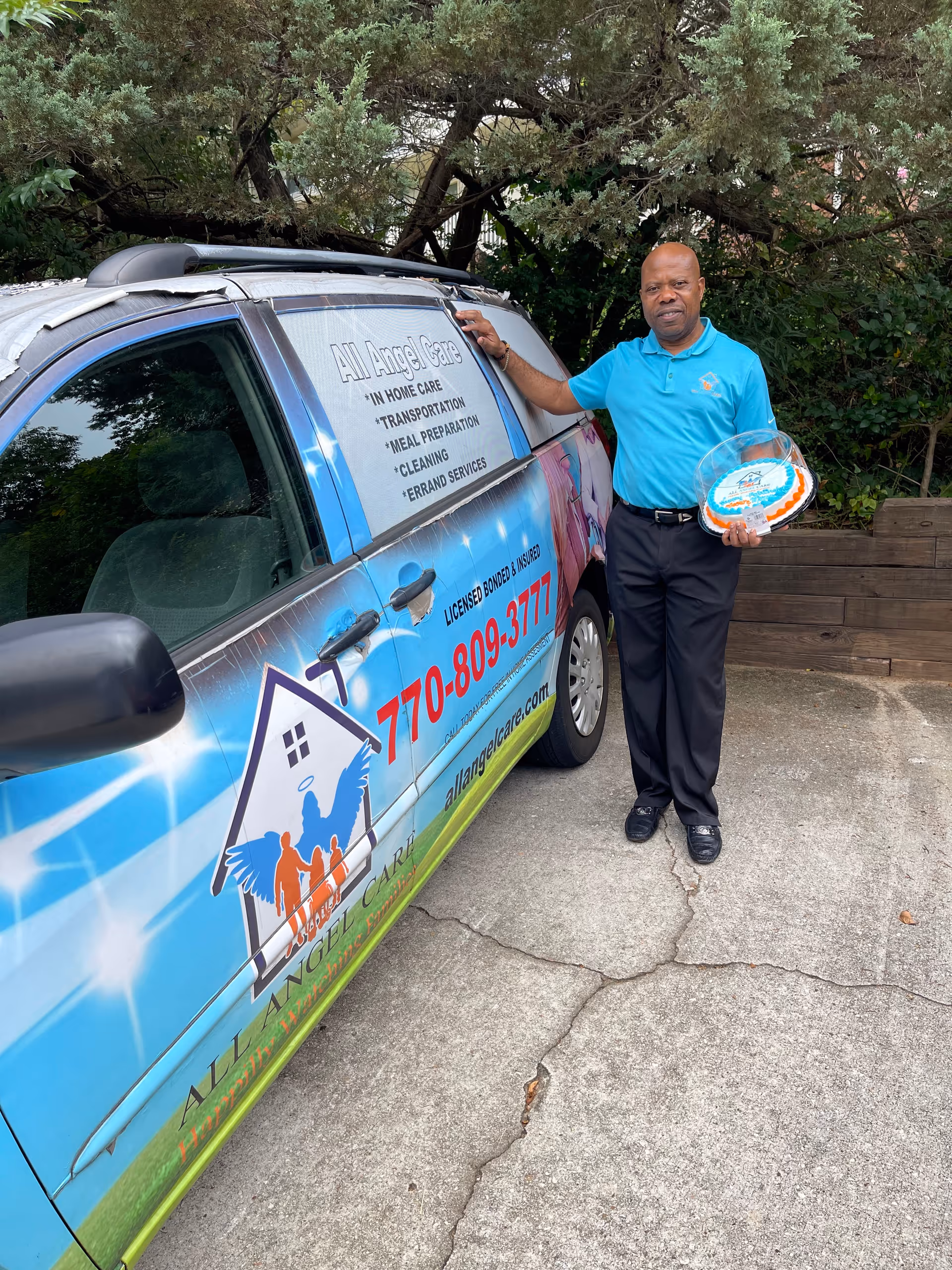 A man in a blue polo stands beside a colorful All Angel Care van outdoors.