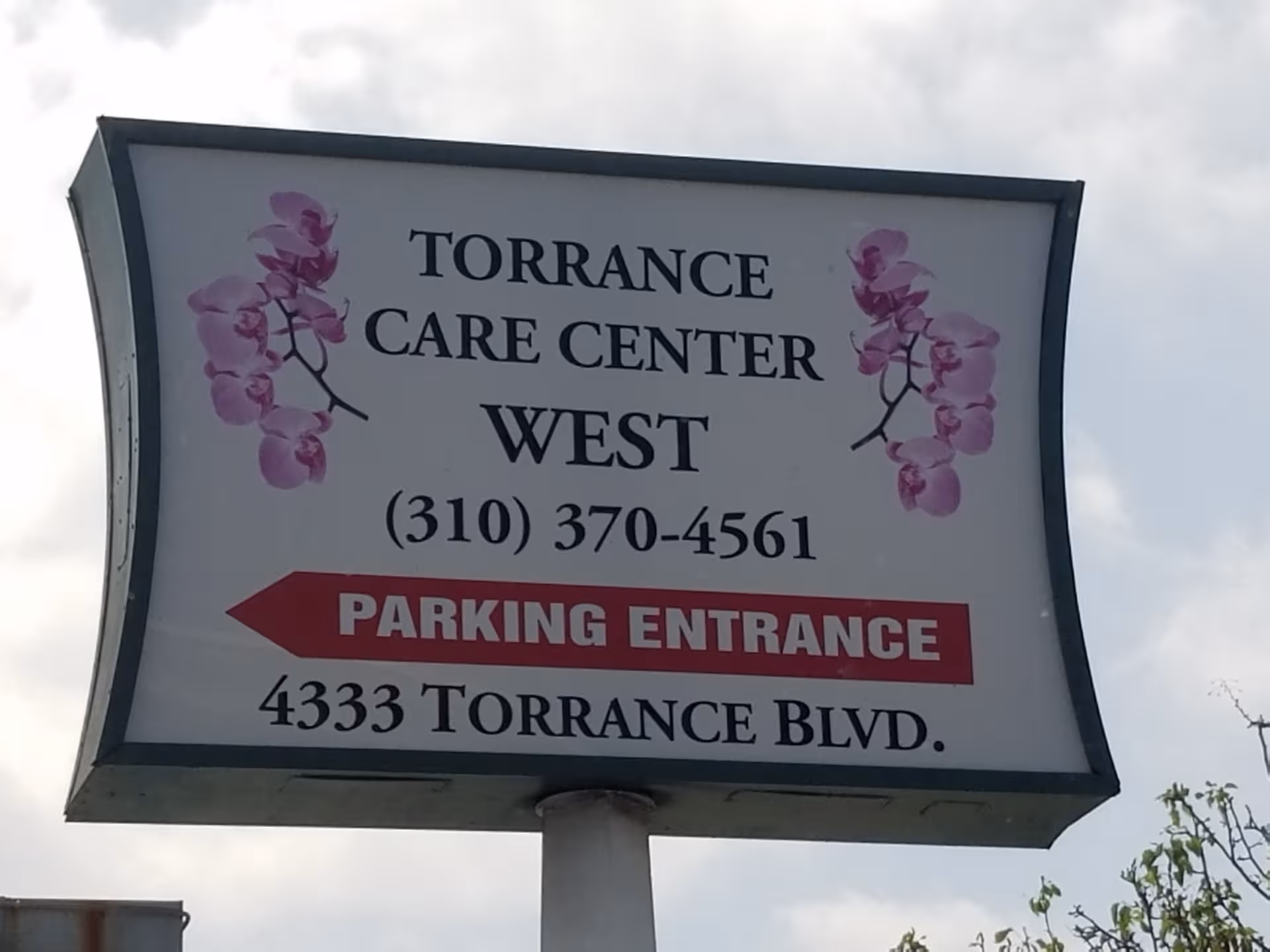 A large outdoor sign for Torrance Care Center West with a parking entrance.