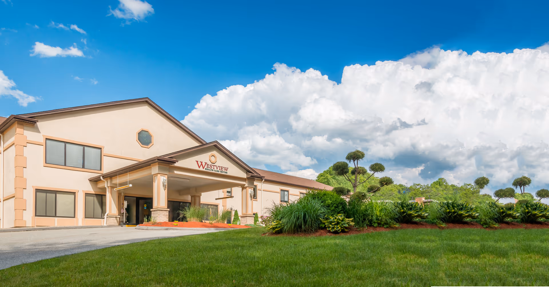 A single-story Westview Health Care Center building with landscaped lawn and blue sky.