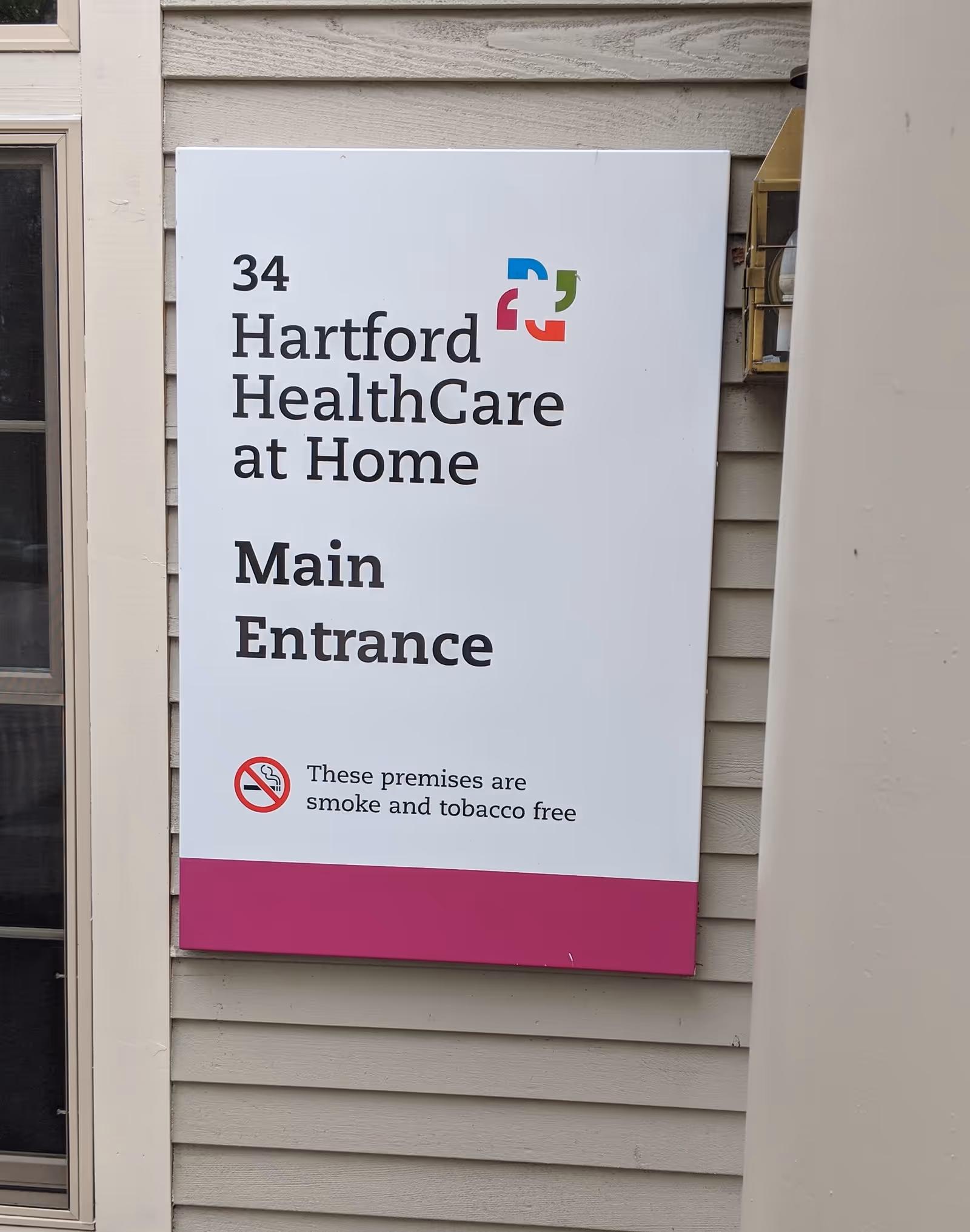 Sign reading Hartford HealthCare at Home Main Entrance mounted on the exterior of a building