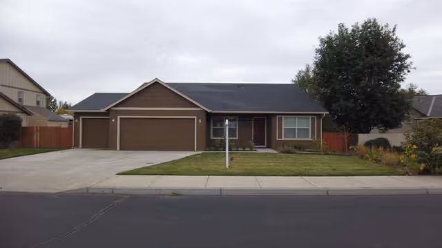 A single-story brown house with a two-car garage and a manicured front lawn.