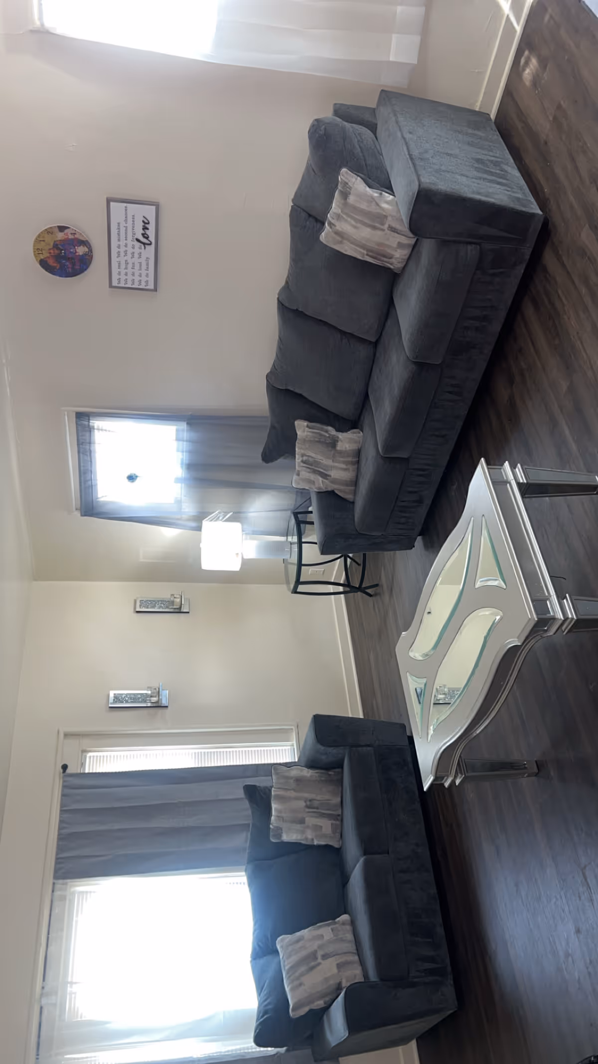 Bright living room in a senior facility with two dark sofas and a glass coffee table.