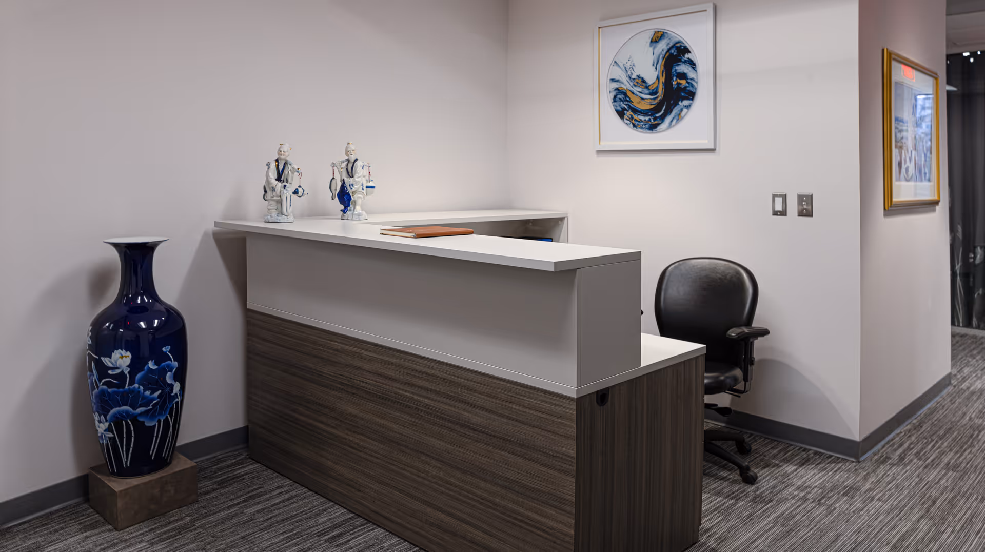Reception desk in a modern lobby with blue vase and wall art.