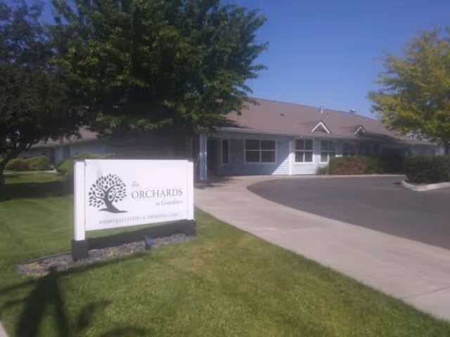 Exterior view of a senior living facility with a front sign and driveway.