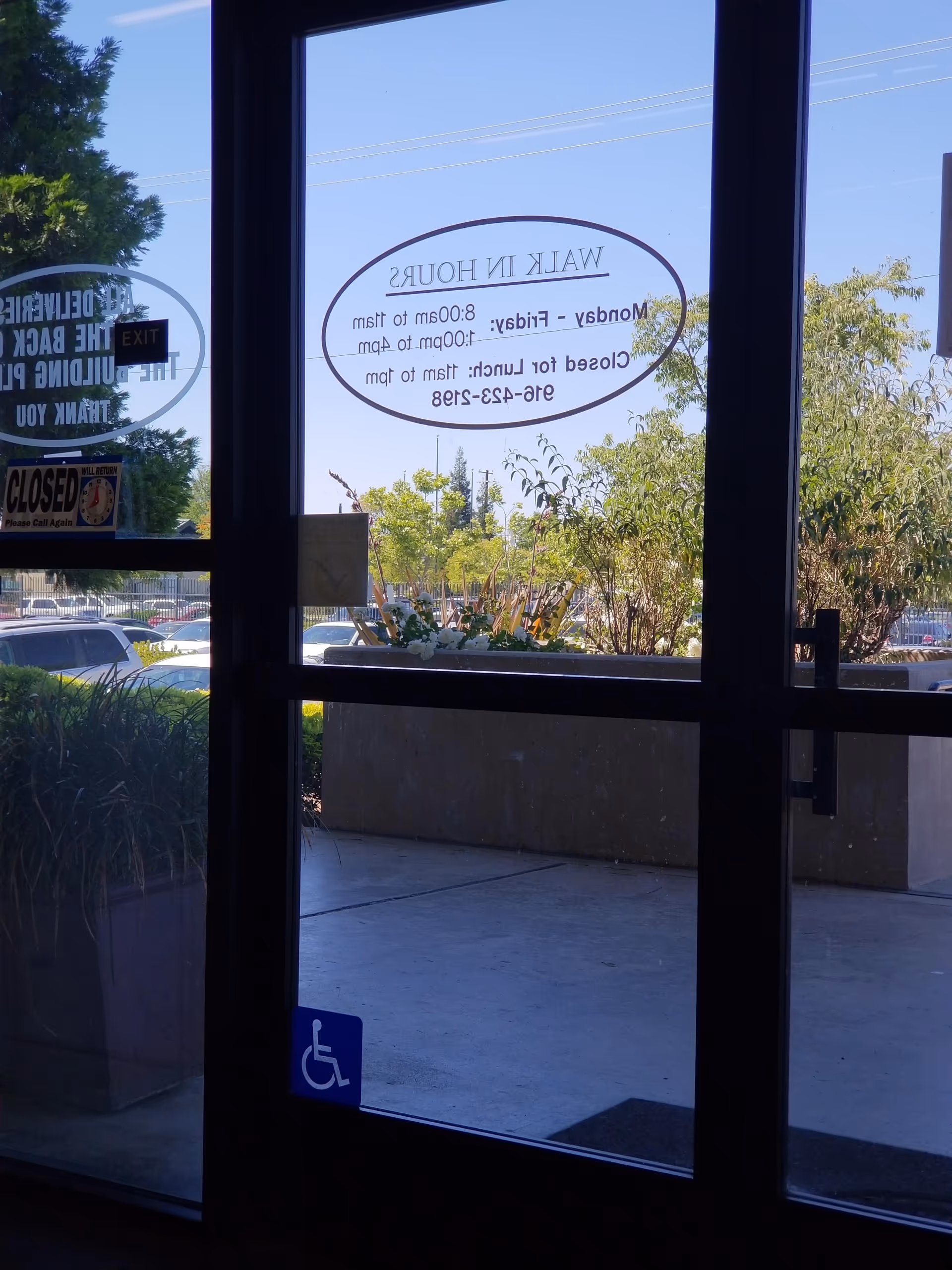 Interior view of glass entrance door with handicap symbol and outdoor parking.
