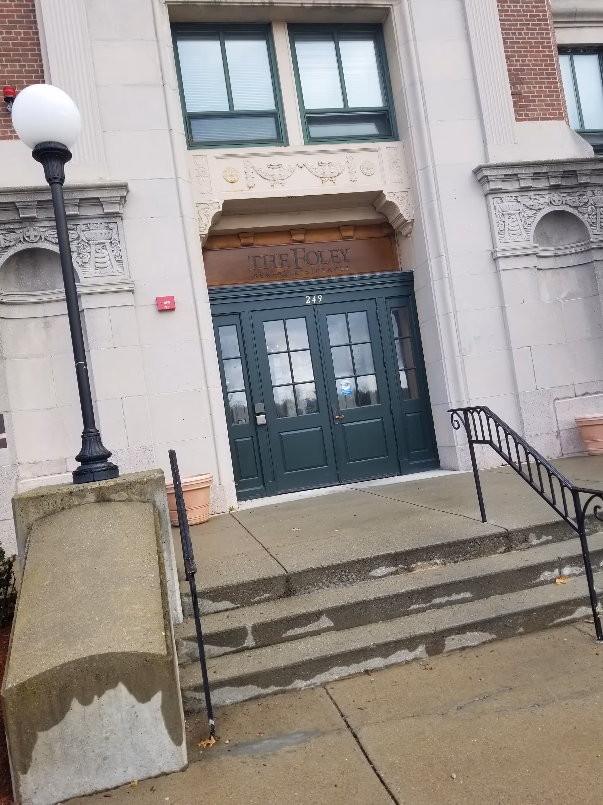 Front entrance of The Foley Senior Residences with double green doors and steps