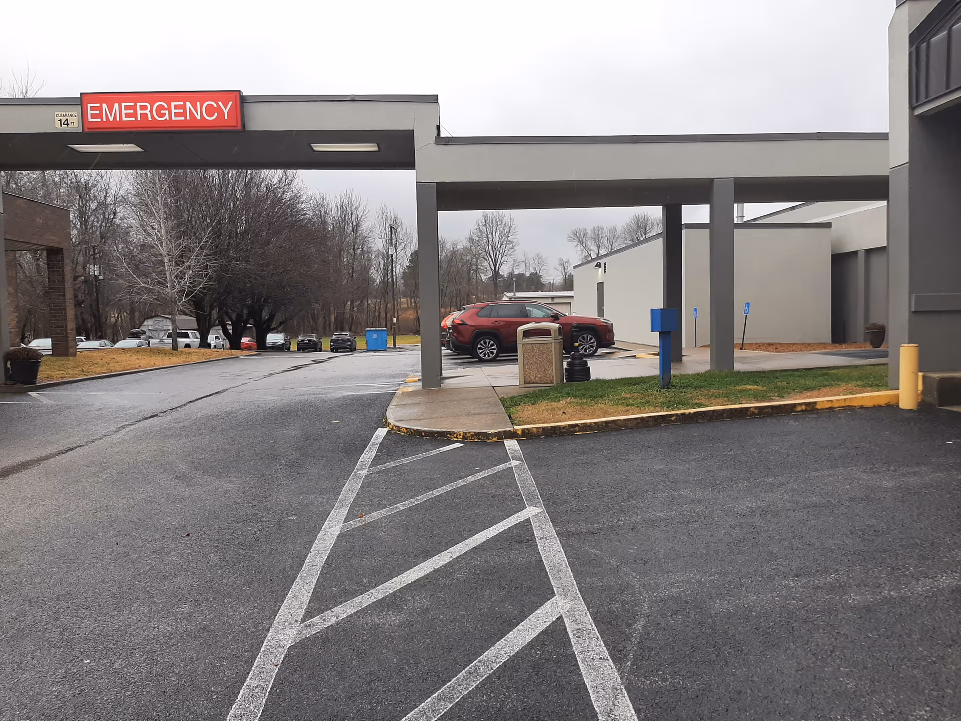 Exterior view of a hospital entrance with an Emergency sign and drive-up entry.