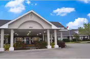 Front entrance of Traditions of La Crescent senior living with pillars and a covered drop-off.