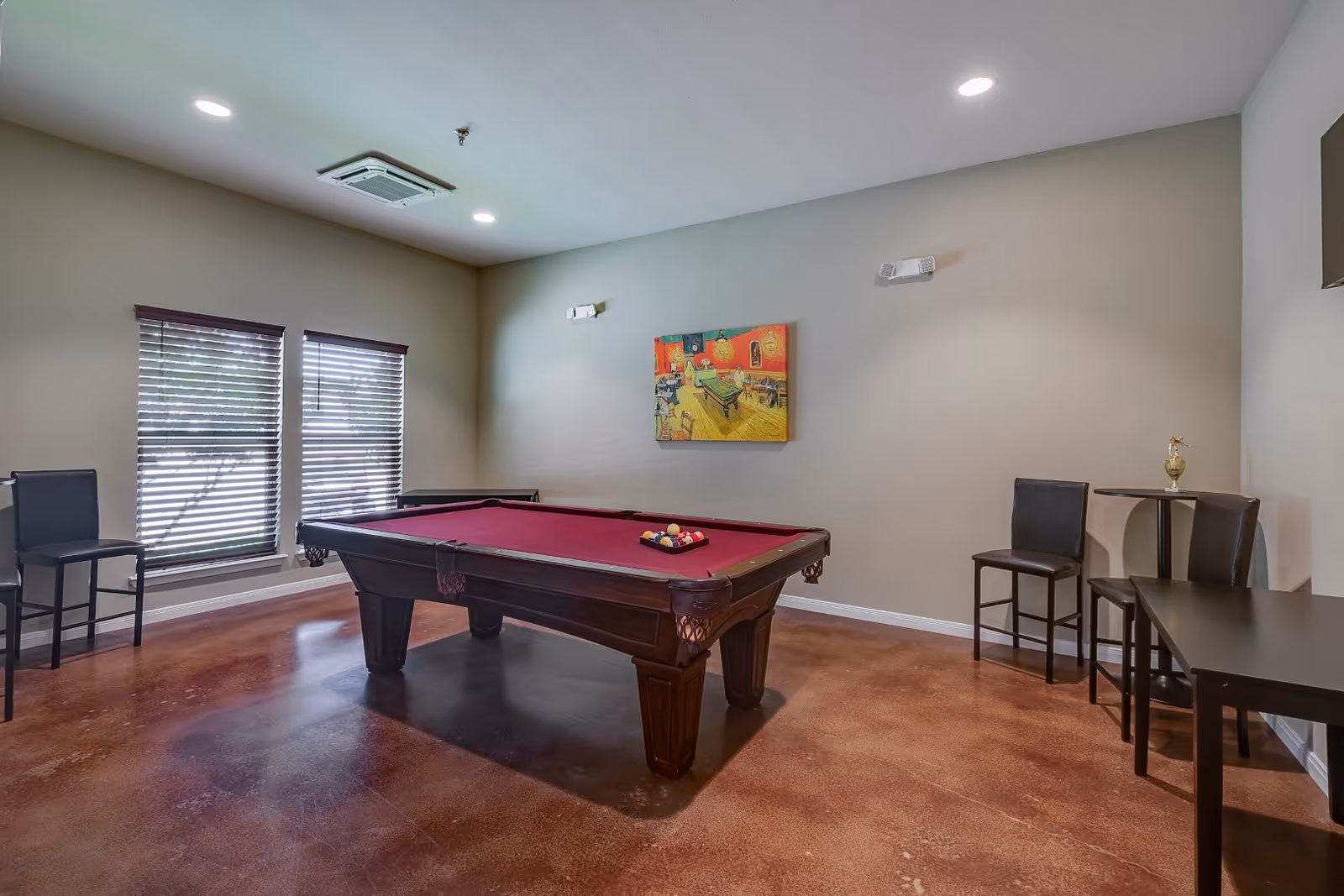 A spacious senior living recreation room with a pool table, seating, and wall art.