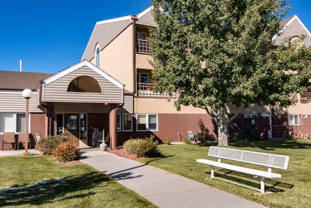 Exterior view of Edgewood Park Place front entrance with lawn and bench.
