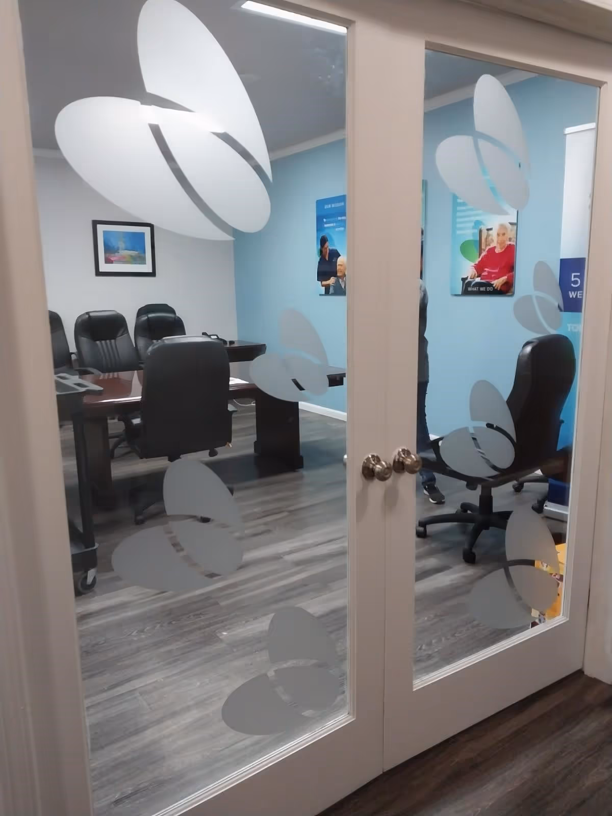 Interior conference room visible through glass doors with frosted butterfly decals.