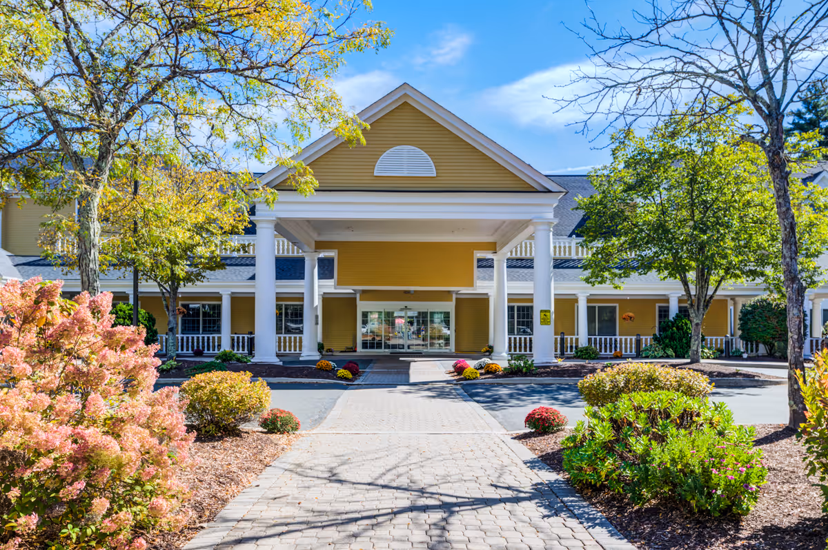 Front entrance of River Ridge at Avon, a yellow senior living facility with columns.