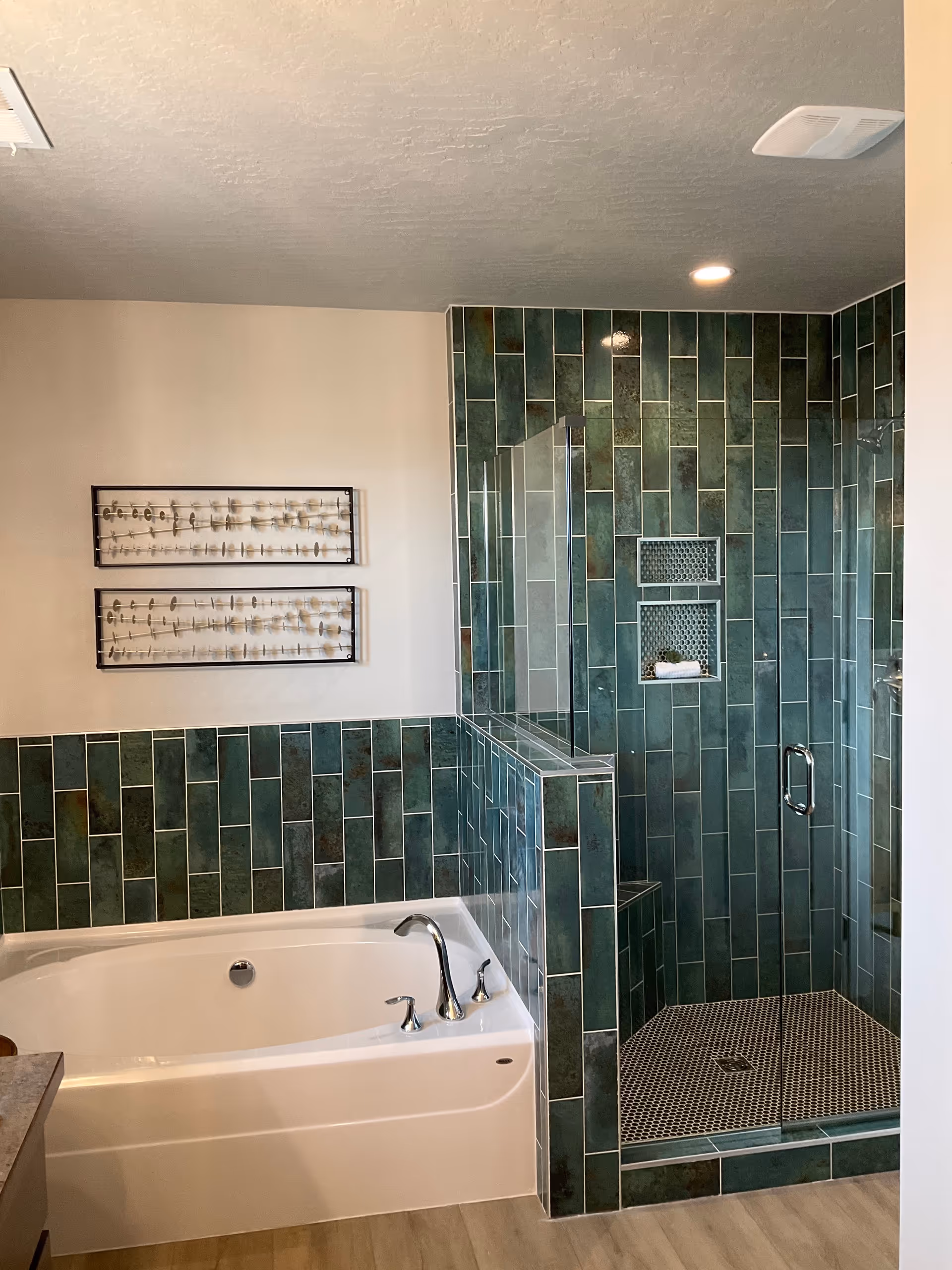 Green-tiled bathroom with a bathtub and a glass-enclosed shower.