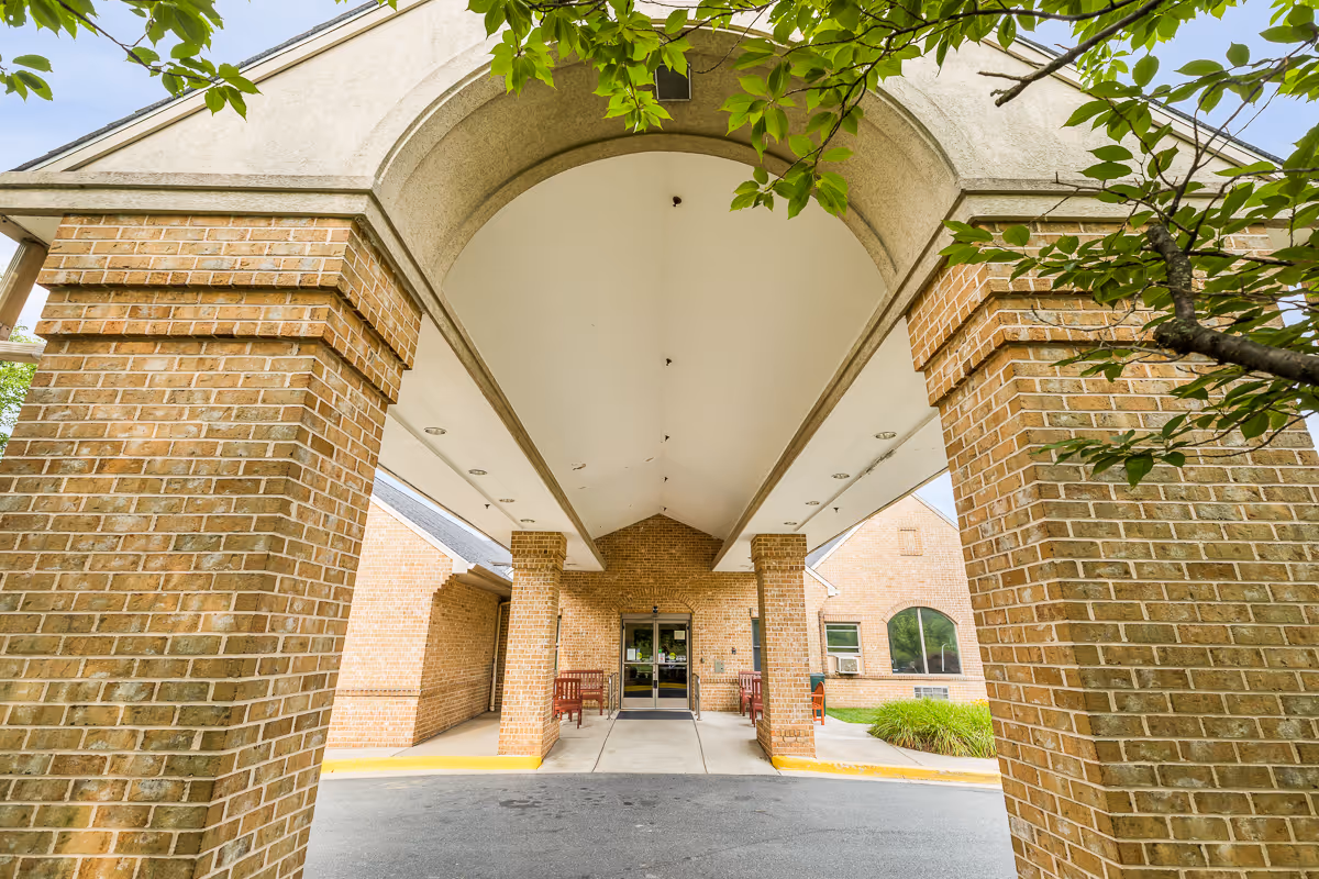 Brick entryway with a covered arched driveway and columns leading to the facility lobby.