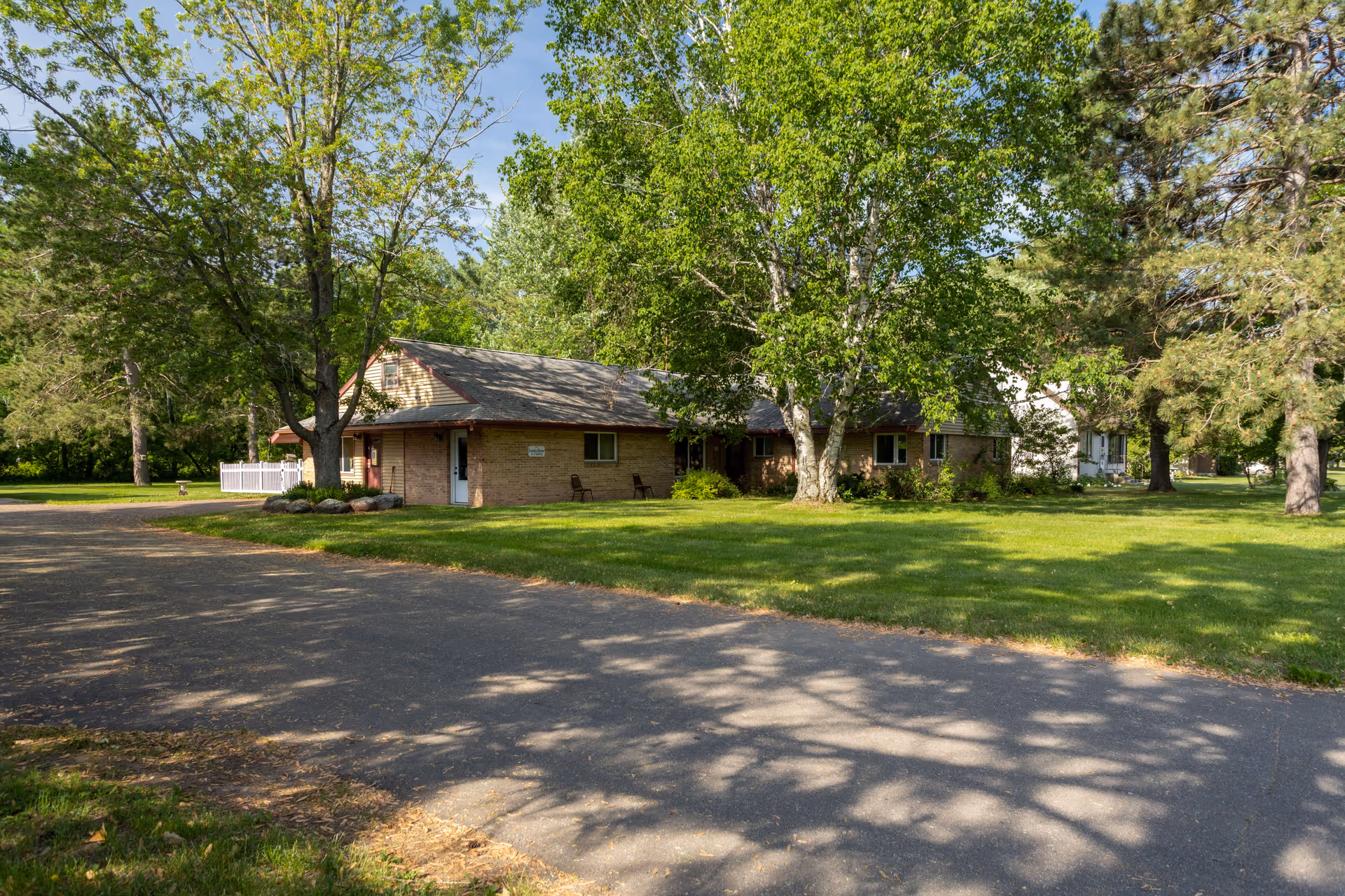 Exterior view of VitaCare Living of Mora building surrounded by trees and lawn.