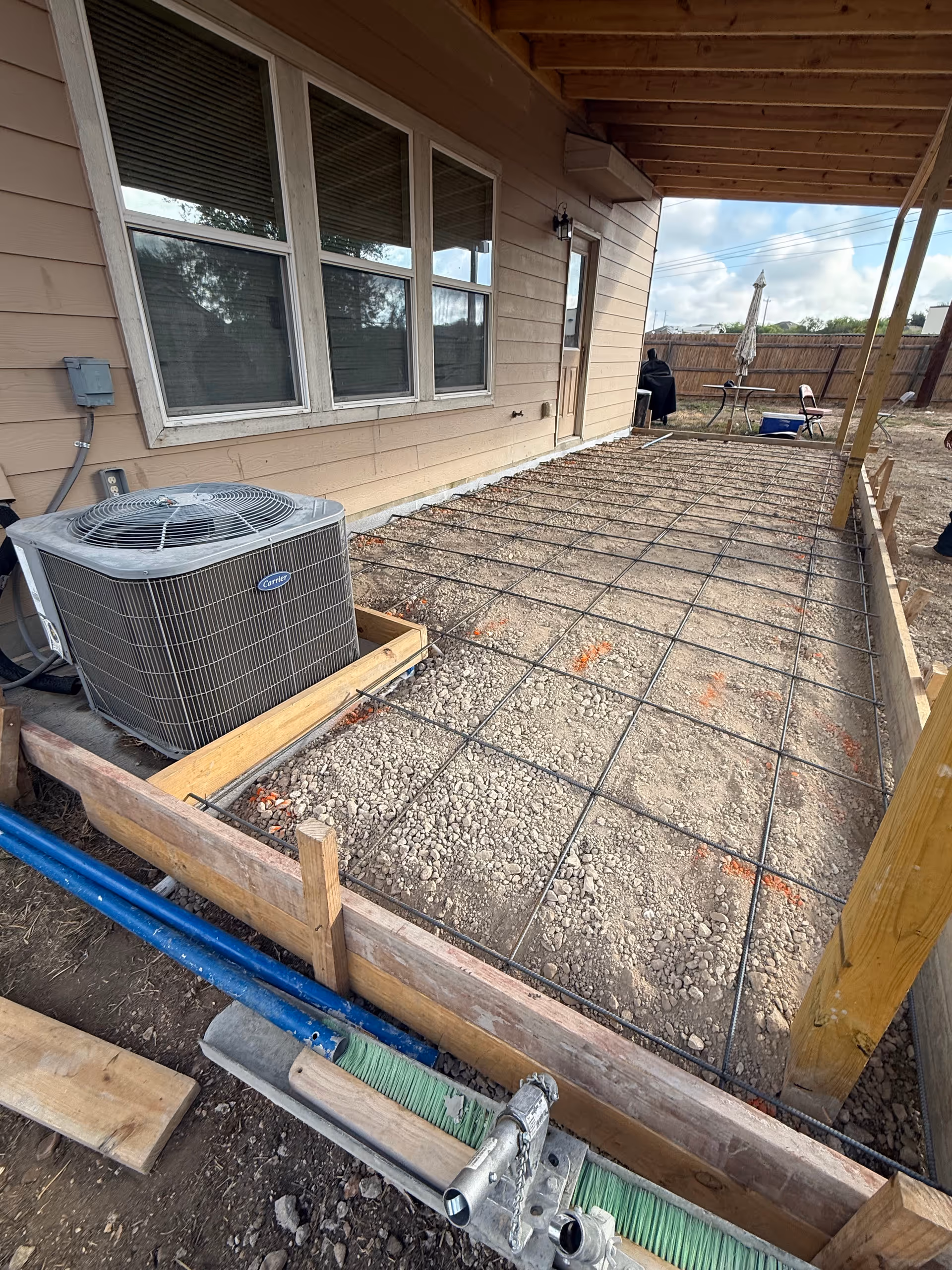 Exterior of Well Care Home with a gravel patio, rebar grid, and outdoor air conditioner.