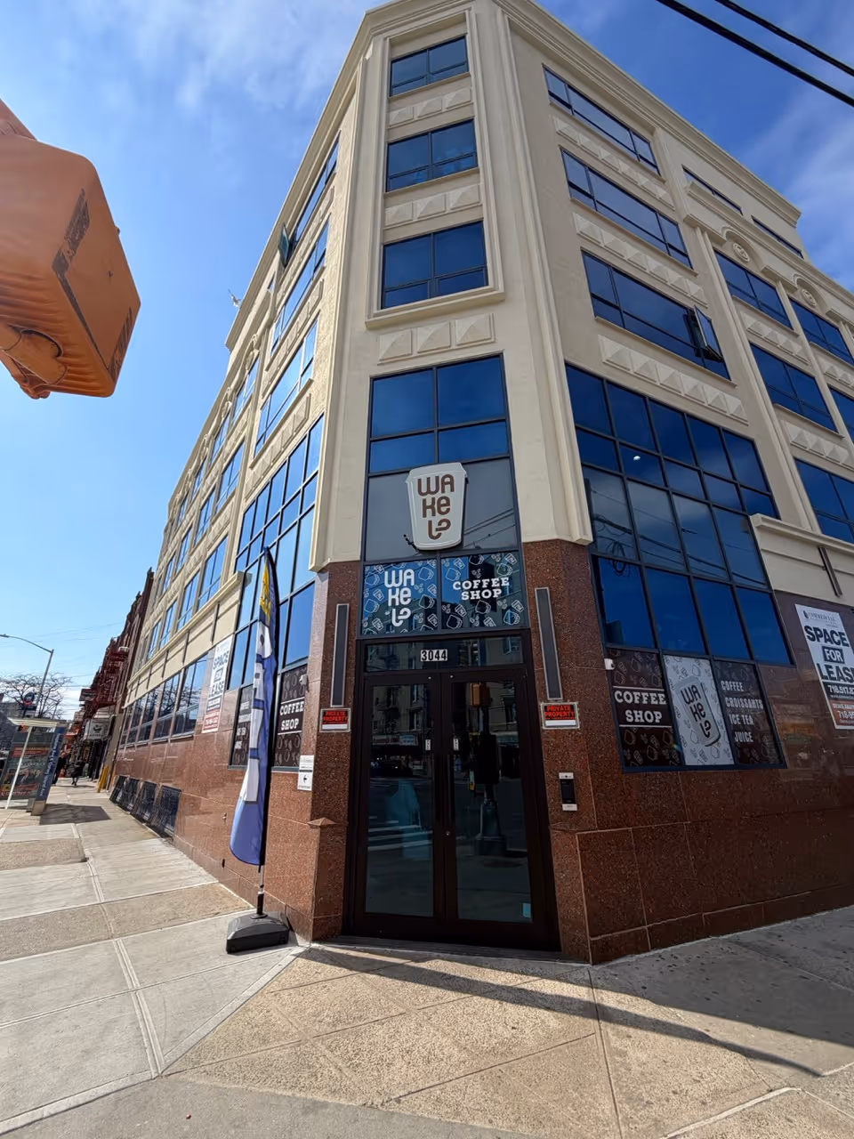 Corner street view of a modern multi-story building with a coffee shop on the ground floor