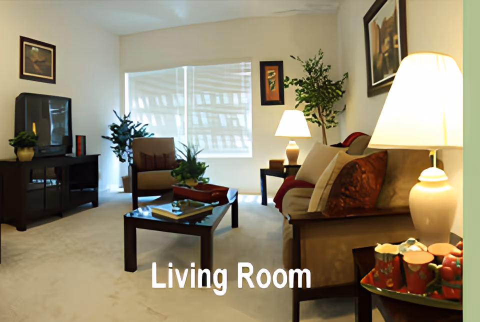 Well-lit living room with a sofa, armchair, coffee table, TV stand and lamps.