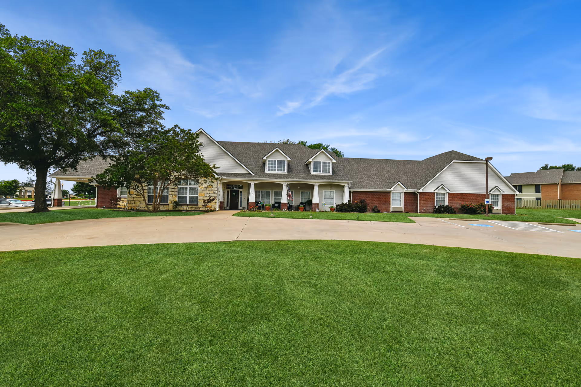 Front exterior of Brookdale Ennis senior living facility with green lawn and curved driveway.