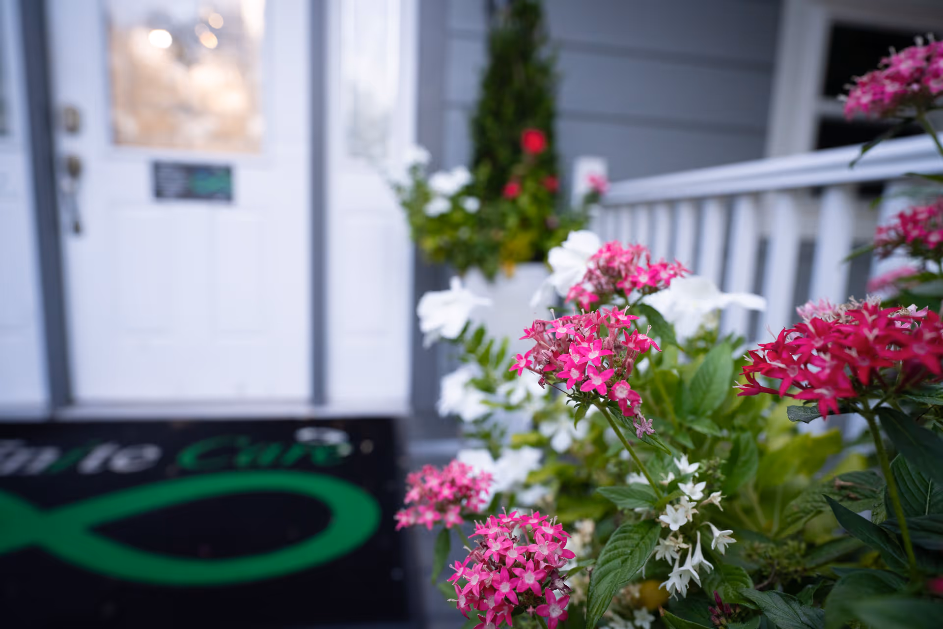 Front entrance of Infinite Care Home Health with white door and vibrant flowers.