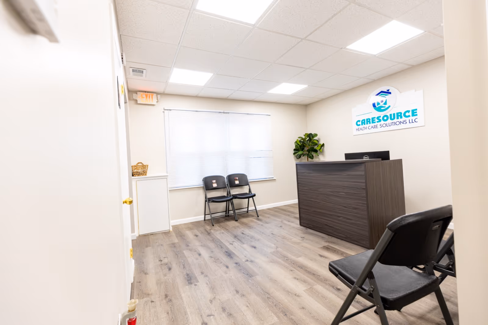 Reception area with dark wood desk, chairs, blinds, a plant, and a CARESOURCE sign.