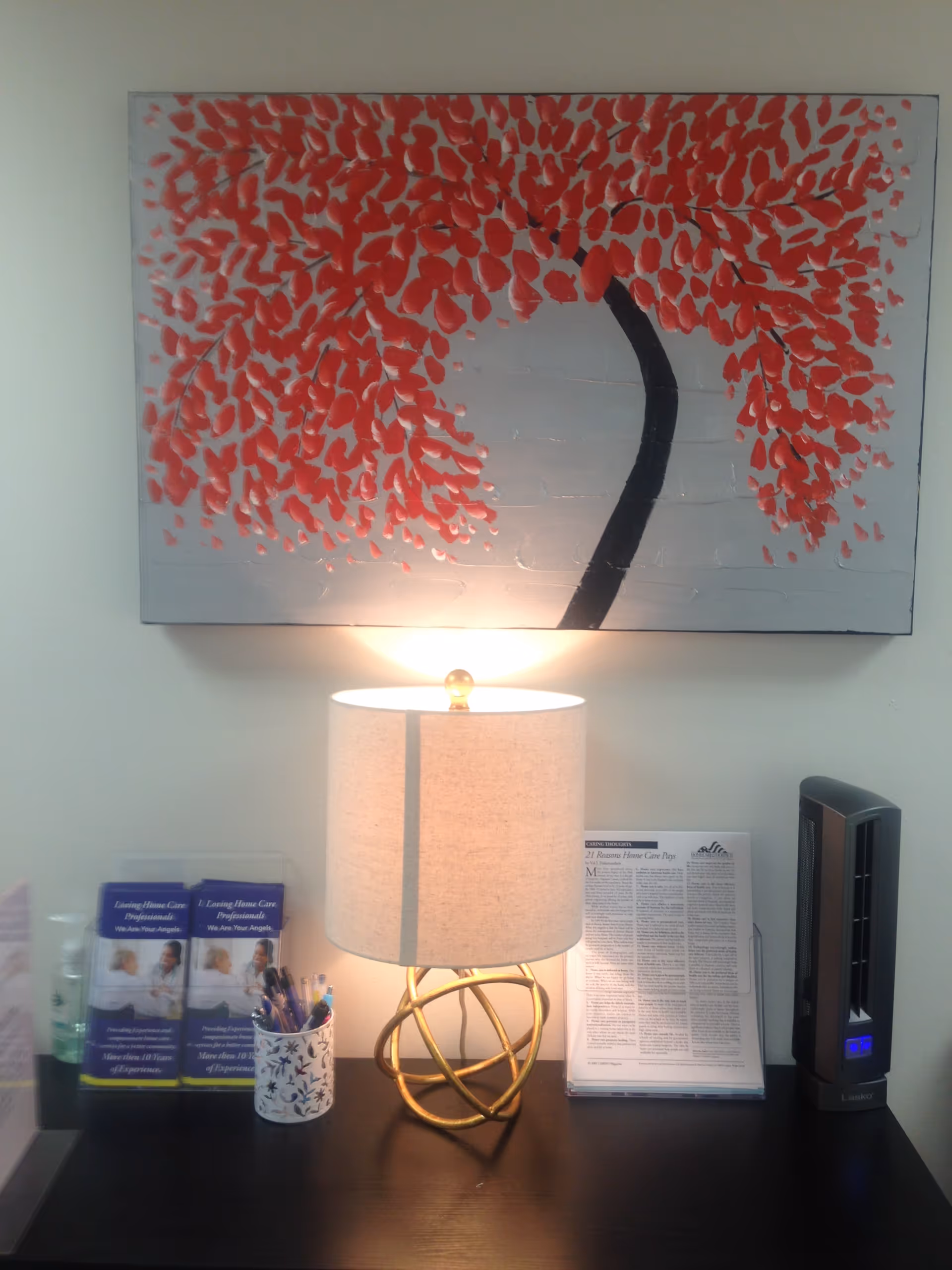 Desk area in a senior care facility featuring a lamp, artwork, and brochures.