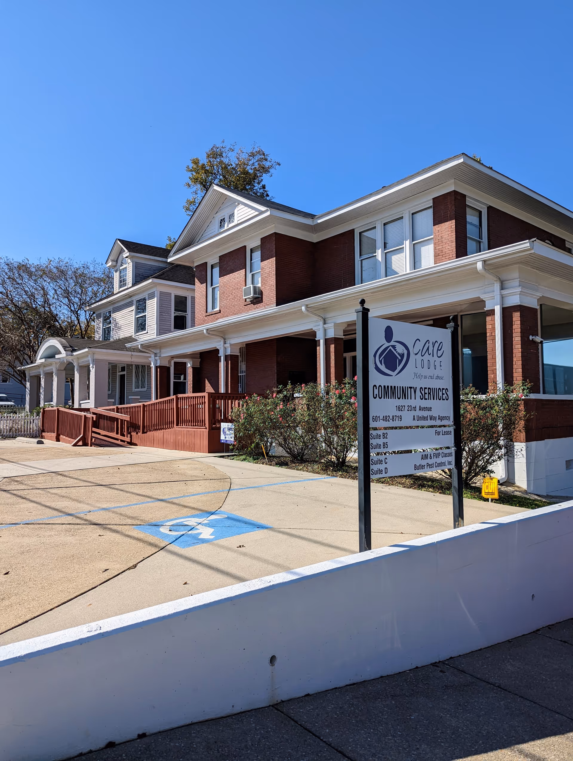 Brick senior living facility exterior with a sign, ramped entrance, and handicap parking.