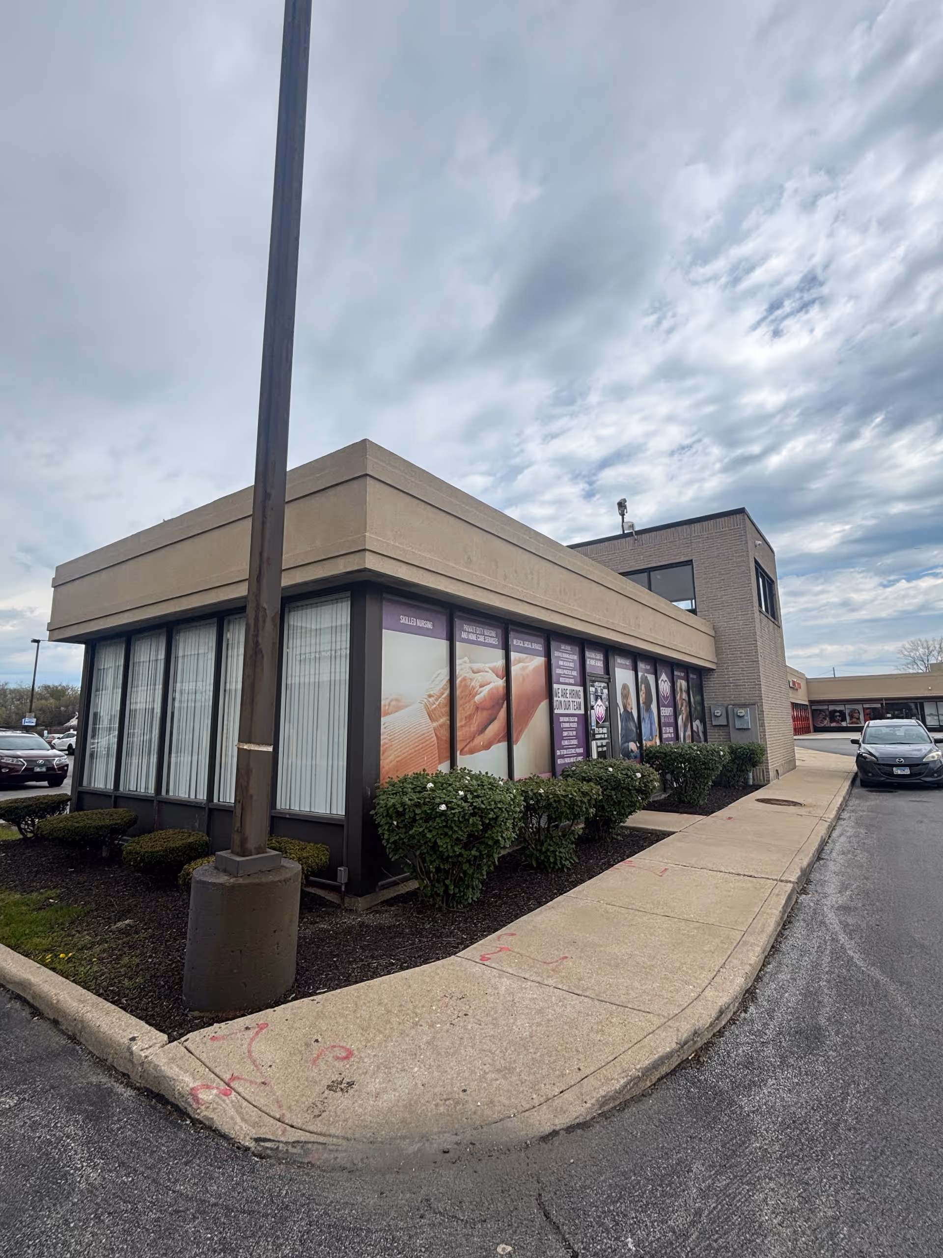 Exterior of a single-story facility with large windows and purple banner signage.