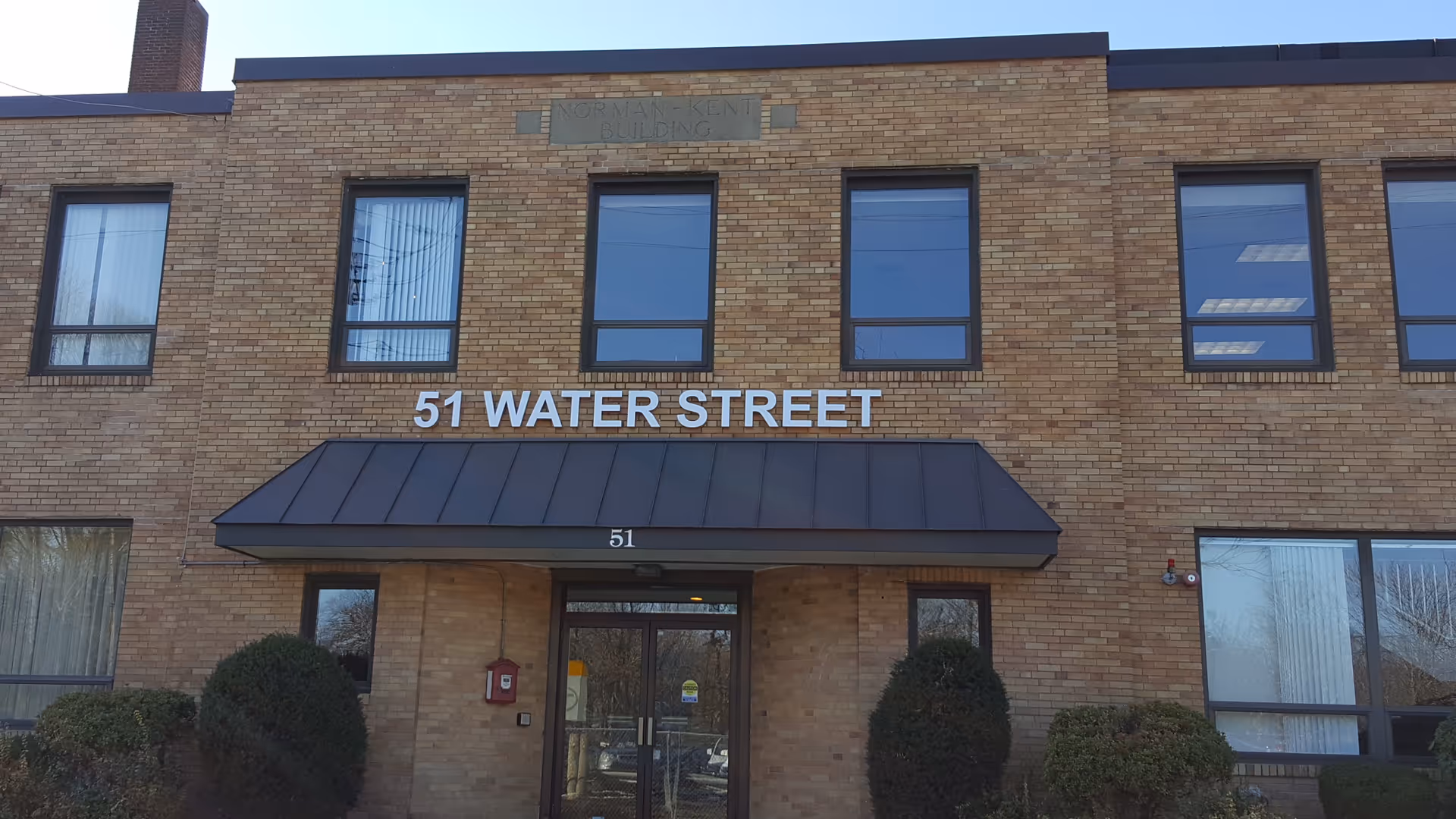 Brick building facade with entrance under a canopy and 51 Water Street sign.