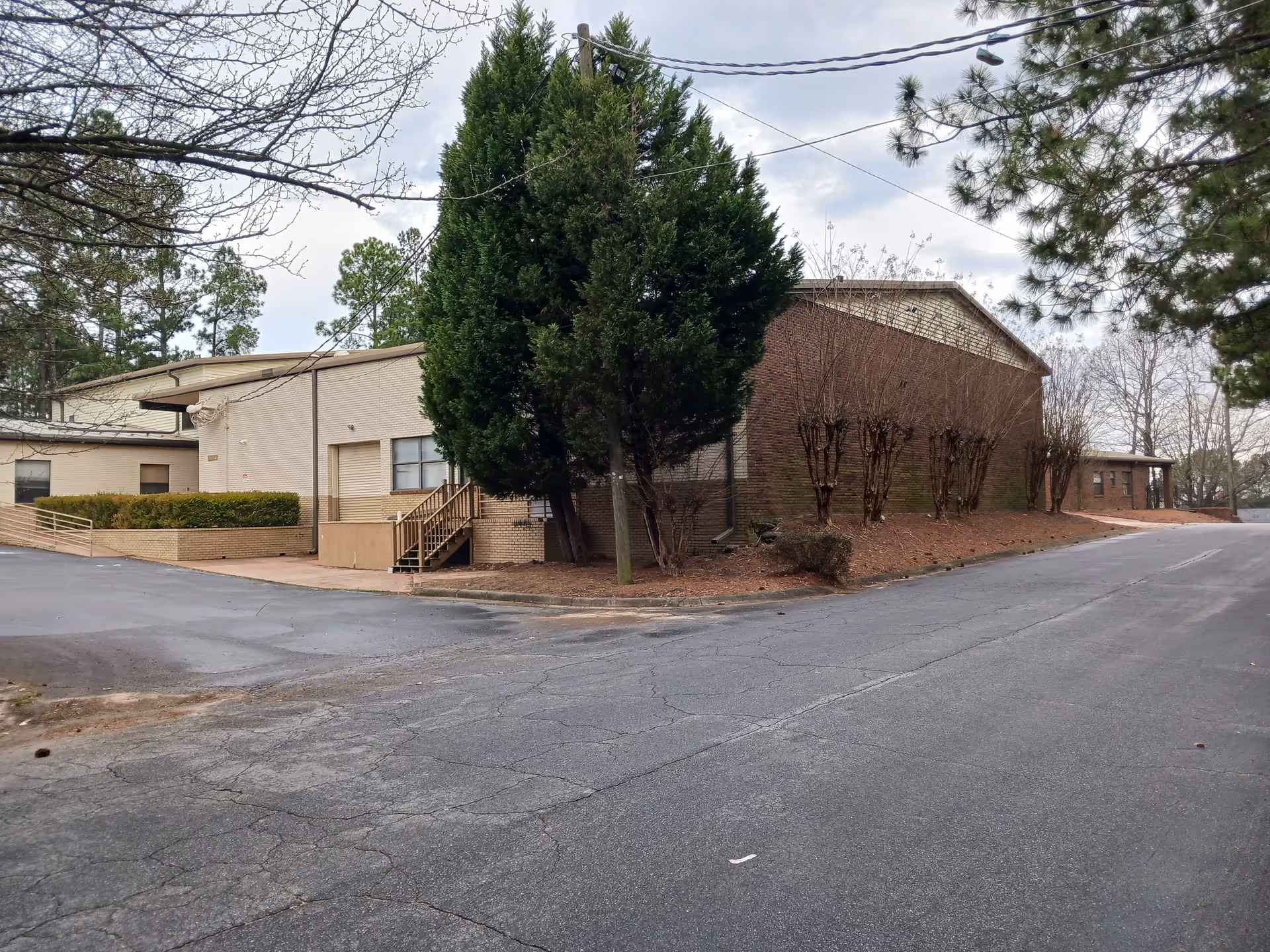 Exterior view of a brick senior living facility with a paved road and trees.