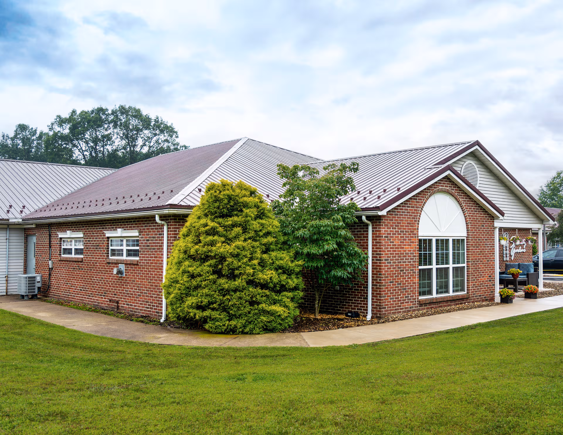 Brick senior living center with arched window and manicured lawn in front.
