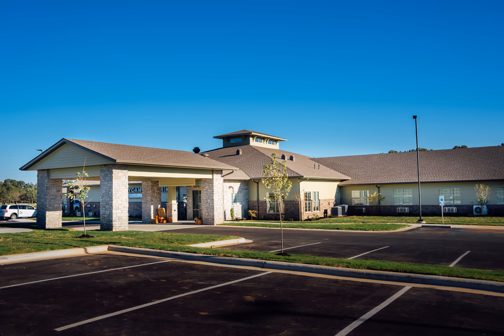 Exterior view of Sycamore Springs Senior Living facility with a covered entrance and parking.