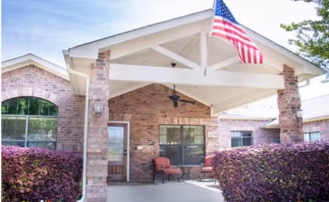 Entrust of DeSoto entrance: brick building, covered porch, seating, and an American flag.