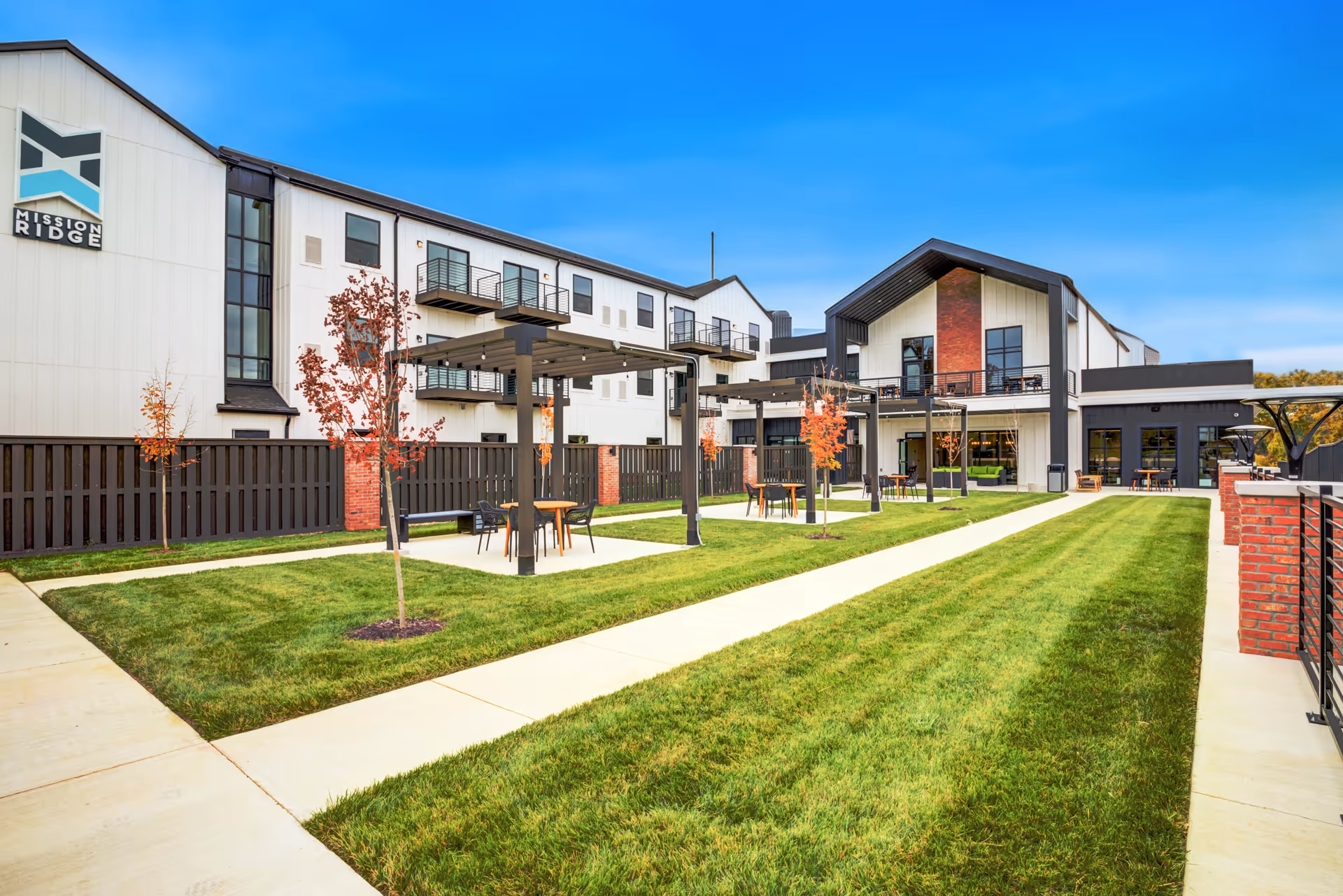 Courtyard and lawn outside the Mission Ridge building with pergolas, outdoor seating, walkways, and balconies.