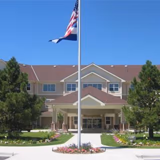 Front exterior of The Courtyards at Mountain View with flagpole and landscaped entrance.