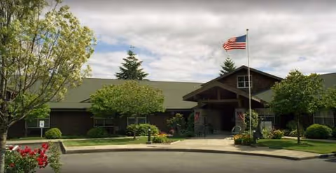 Front exterior view of Rock Cove senior living facility with entrance and flag